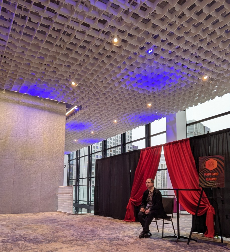 A person sitting in a chair in a room with red curtains and black
curtains Description automatically
generated